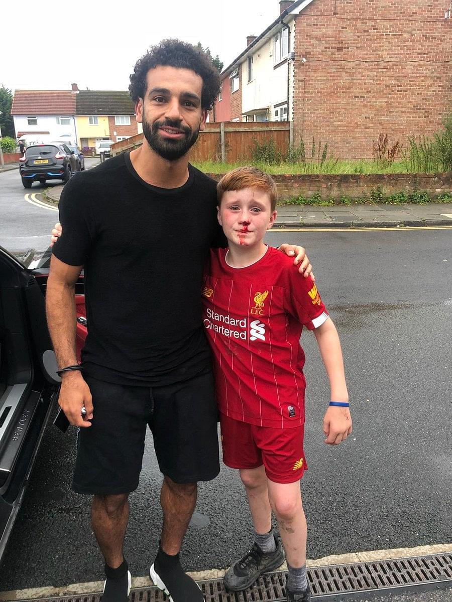 Mohamed Salah poses with young fan who ran into lamp post trying to get a wave