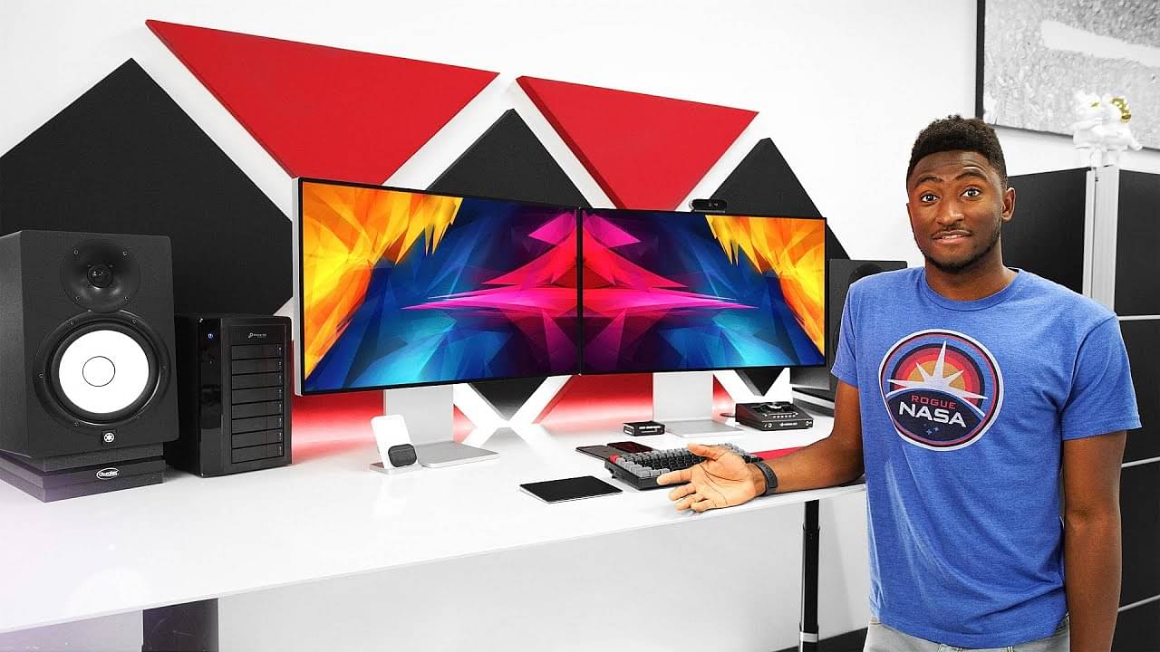 Popular YouTube product reviewer MKBHD standing in front of curved screen, speakers and more