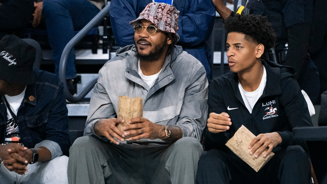 Carmelo Anthony and his son, Kiyan, watch the Don Bosco Prep Ironmen compete against the McEachern Indians in a game during the 50th annual City of Palms Classic