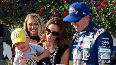 NASCAR Cup Series driver Kyle Busch and wife Samantha Busch watch as their son put the winner's sticker on his father's car after winning the Gander Outdoors 400 at Pocono Raceway.