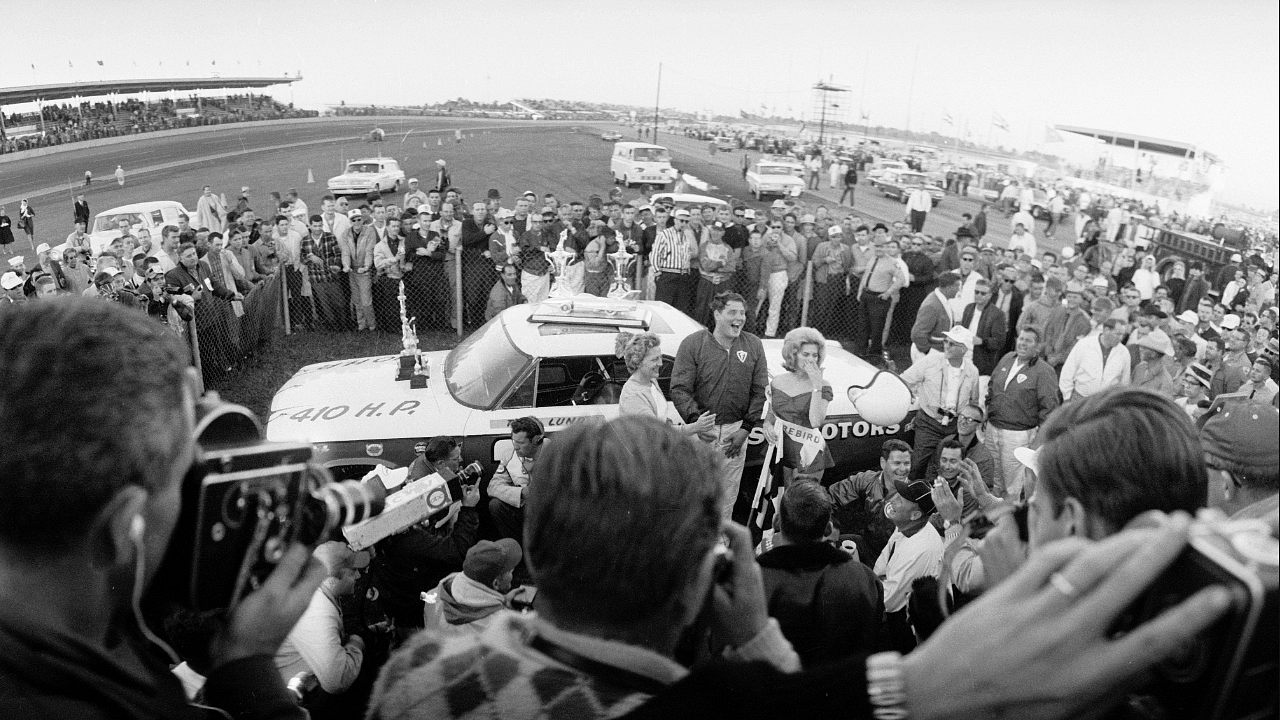 DAYTONA BEACH - FEBRUARY 24: American racing car driver Tiny Lund (1929 - 1975) (center) stands with his wife Ruth and Miss Firebird after winning the Daytona 500, Daytona Beach, Florida, February 24, 1963. Michael Rougier/The LIFE Picture Collection