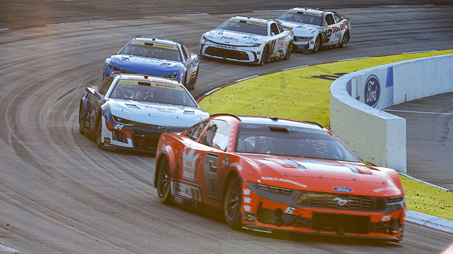 Cars leave turn two as the sun starts to set during the Xfinity 500 at Martinsville Speedway.