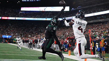 New York Jets wide receiver Garrett Wilson (5) catches a touchdown pass while being defended by Houston Texans cornerback Kamari Lassiter (4) during the second half at MetLife Stadium.