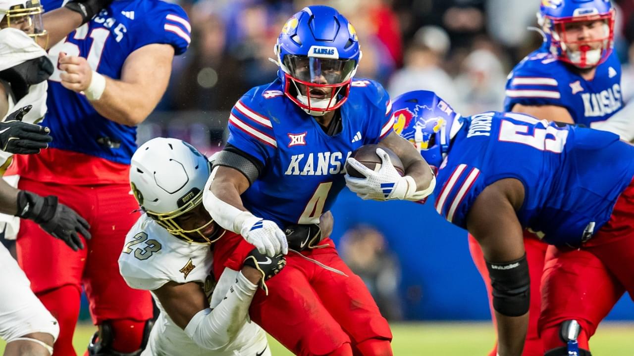 Nov 23, 2024; Kansas City, Missouri, USA; Kansas running back Devin Neal (4) attempts to break through the tackle of Colorado safety Carter Stoutmire (23) during the 3rd quarter between the Kansas Jayhawks and the Colorado Buffaloes at GEHA Field at Arrowhead Stadium.