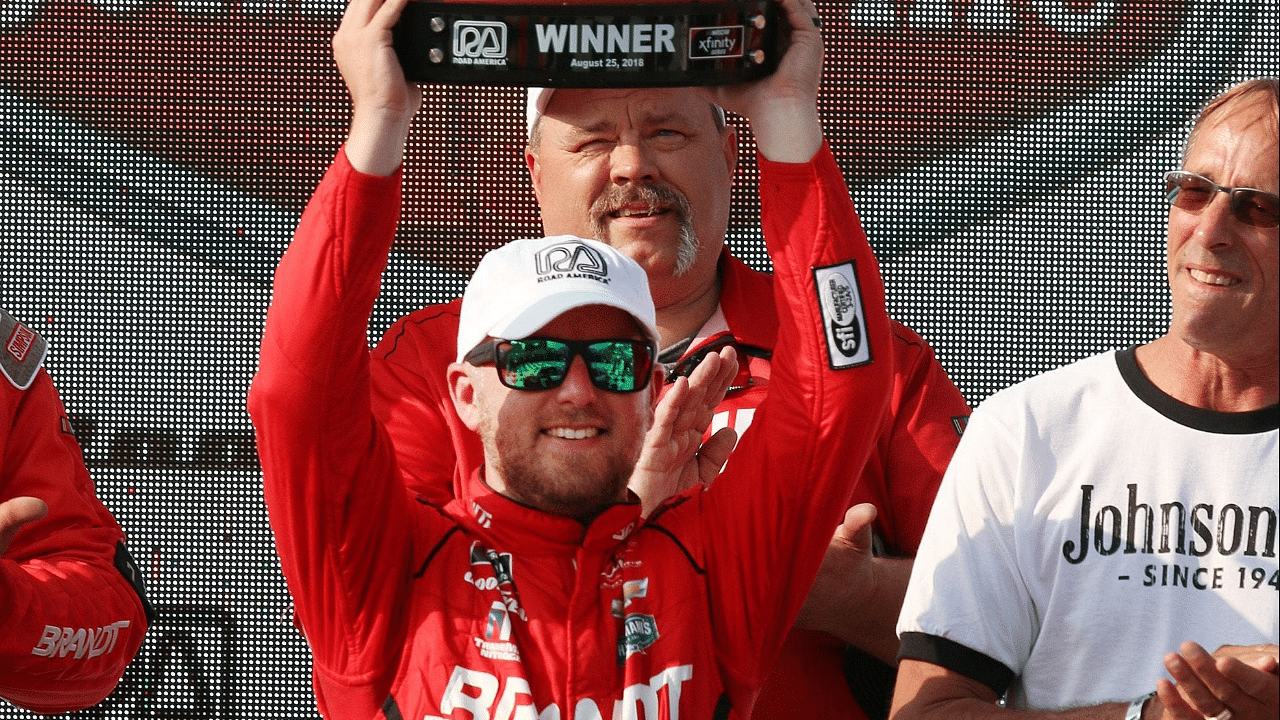 Justin Allgaier raises the trophy he won high at the Johnsonville 180, Saturday, August 25, 2018 at Elkhart Lake's Road America. 082518 She Johnsonville 180 Gk 01