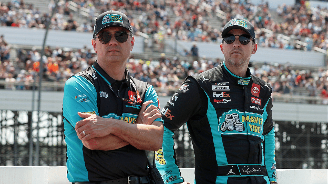 Jul 14, 2024; Long Pond, Pennsylvania, USA; NASCAR Cup Series driver Denny Hamlin (right) stands with his crew chief Chris Gabehart (left) on pit road prior to The Great American Getaway 400 at Pocono Raceway. Mandatory Credit: Matthew O'Haren-Imagn Images