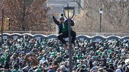 A fan of the Philadelphia Eagles climbs a light pole during the Super Bowl LIX championship parade and rally.