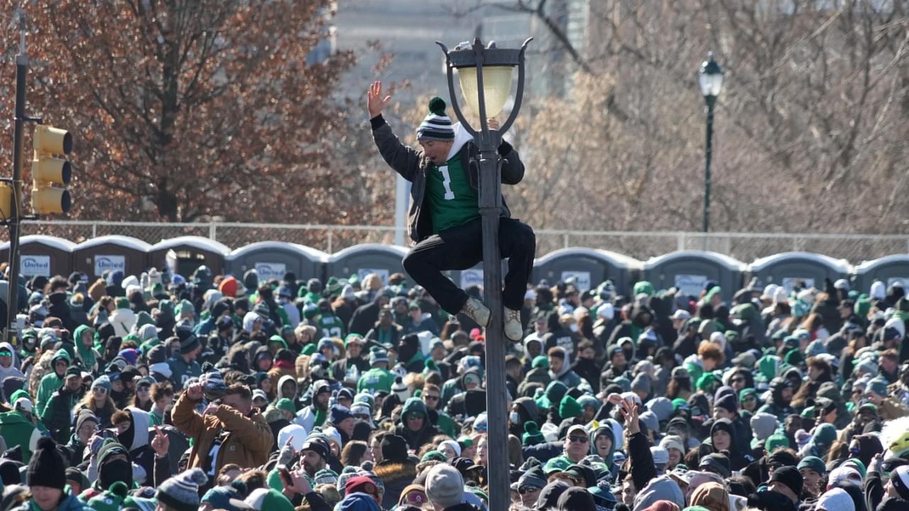 A fan of the Philadelphia Eagles climbs a light pole during the Super Bowl LIX championship parade and rally.