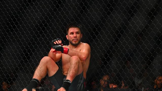 Henry Cejudo (red gloves) sits down after being poked in the eye by Song Yadong (blue gloves) in the bantamweight bout during UFC Fight Night at Climate Pledge Arena.