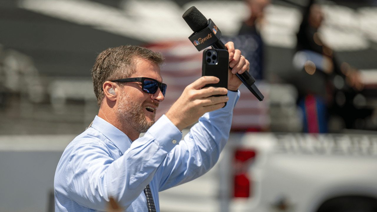 Jul 31, 2022; Indianapolis, Indiana, USA; Dale Earnhardt Jr. raises his hands to cheering fans on the grid before the Verizon 200 at the Indianapolis Motor Speedway Road Course. Mandatory Credit: Marc Lebryk-Imagn Images