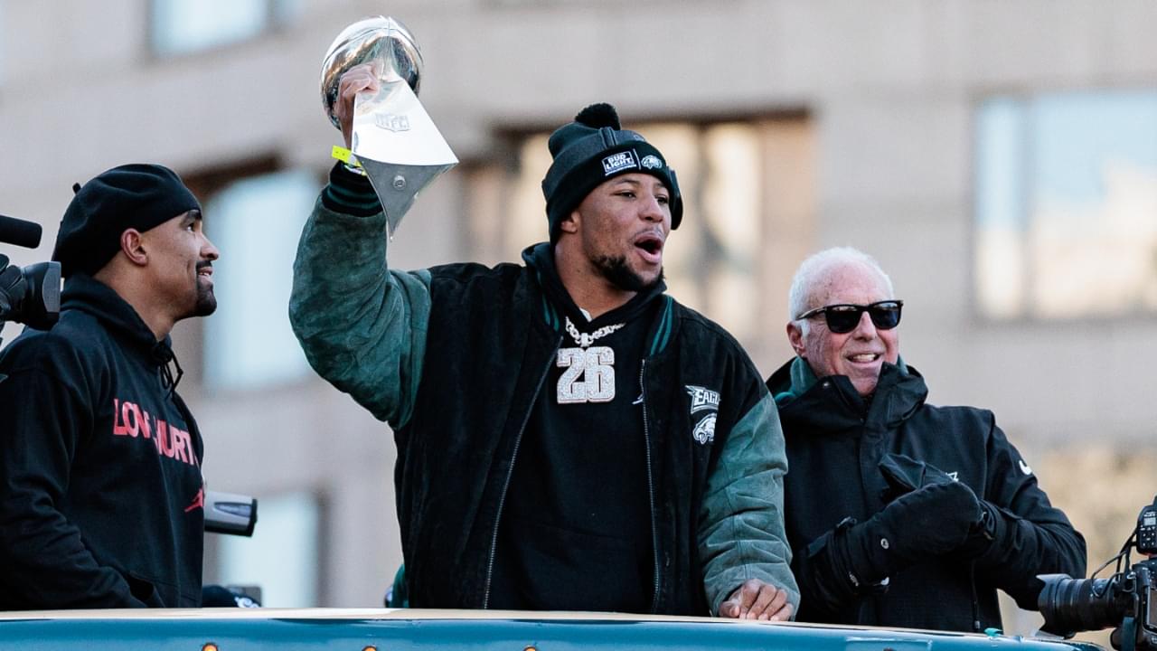 Feb 14, 2025; Philadelphia, PA, USA; Philadelphia Eagles running back Saquon Barkley (26) celebrates next to team owner Jeffrey Lurie and quarterback Jalen Hurts (1) during the Super Bowl LIX championship parade and rally.