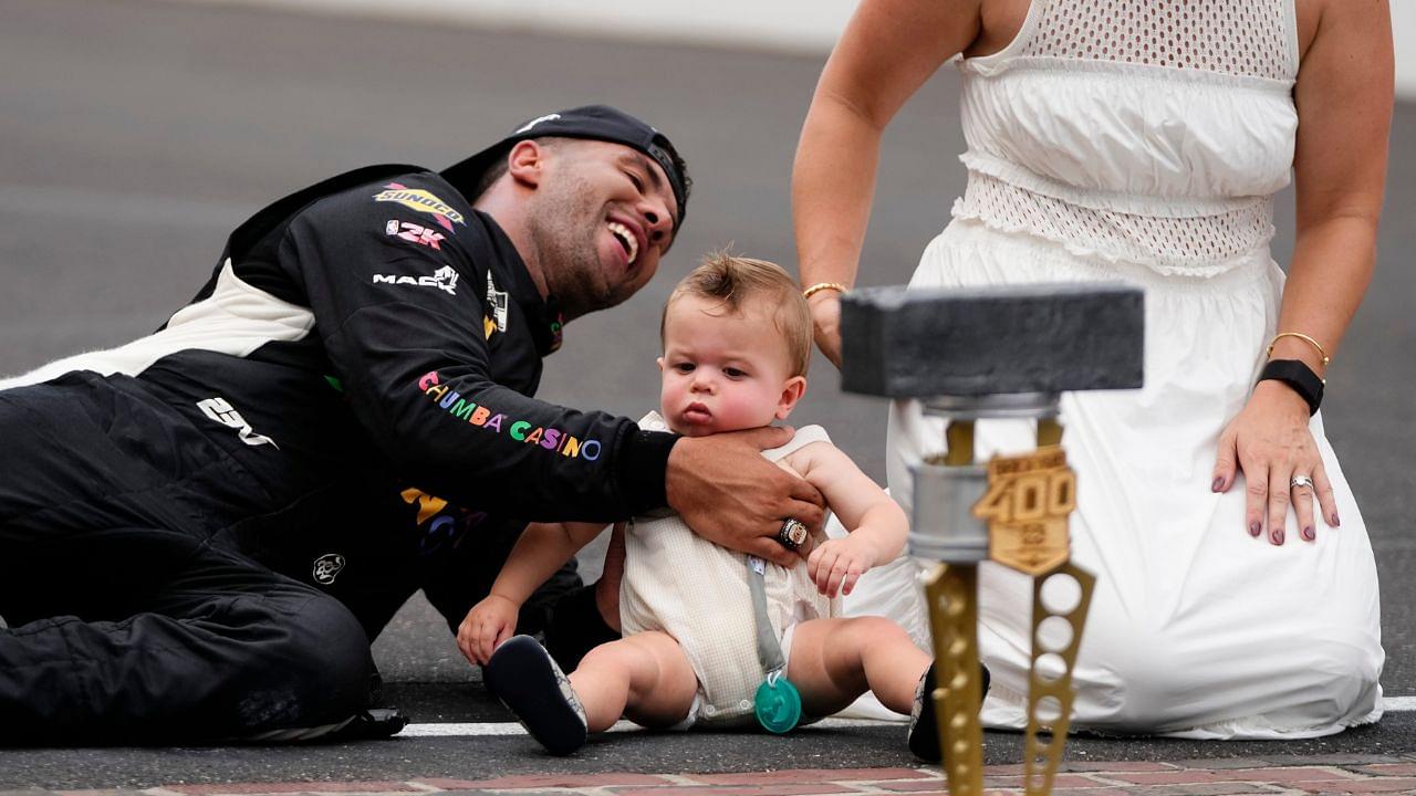 NASCAR Cup Series driver Bubba Wallace (23) kisses the bricks with his wife, Amanda Carter, and son, Becks Hayden Wallace, Sunday, July 27, 2025, following the Brickyard 400 at Indianapolis Motor Speedway.