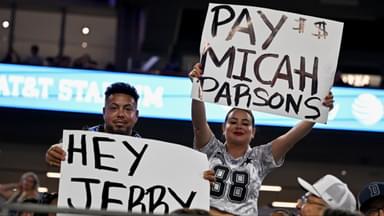 Dallas Cowboys fans hold up signs to owner Jerry Jones and defensive end Micah Parsons (11) during the second half of the game against the Baltimore Ravens at AT&T Stadium.