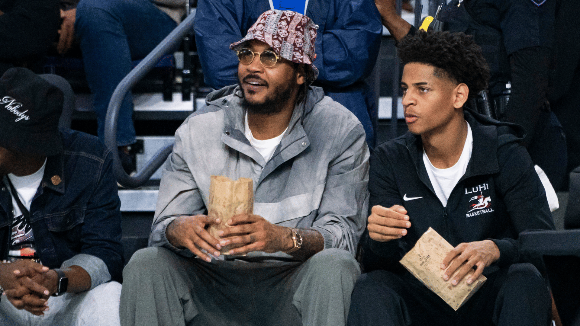 Carmelo Anthony and his son, Kiyan, watch the Don Bosco Prep Ironmen compete against the McEachern Indians in a game during the 50th annual City of Palms Classic at Suncoast Credit Union Arena in Fort Myers on Tuesday, Dec. 19, 2023