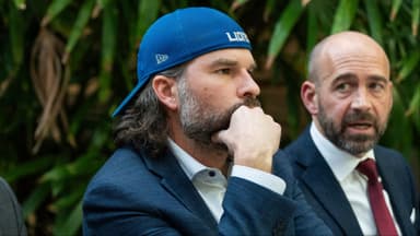 Detroit Lions fan Ryan Kennedy, center, listens during a press conference while being represented by Head Murphy Law attorney Sean Murphy, left, and Head Murphy Law founder and Managing Member Shawn Head,right, during a press conference at Head Murphy Law in Farmington Hills on Friday, December 26, 2025, while discussing the fan involved in an altercation with Pittsburgh Steelers player DK Metcalf at the Detroit Lions game at Ford Field last Sunday.