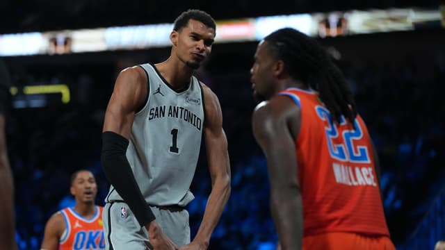 Dec 13, 2025; Las Vegas, Nevada, USA; San Antonio Spurs forward Victor Wembanyama (1) flexes in front of Oklahoma City Thunder guard Cason Wallace (22) during the third quarter at T-Mobile Arena.