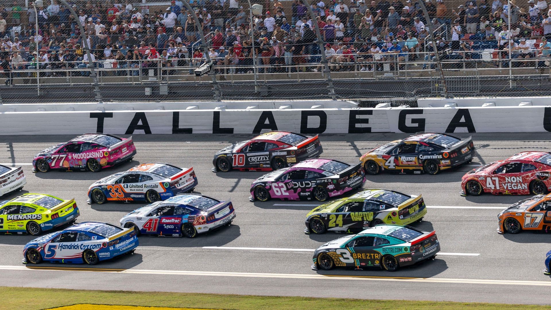 Oct 19, 2025; Talladega, Alabama, USA; Cars race by Talladega signage during stage one of the YellaWood 500 at Talladega Superspeedway