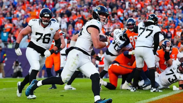 Jacksonville Jaguars quarterback Trevor Lawrence (16) rushes for a touchdown against the Denver Broncos during the second half at Empower Field at Mile High.