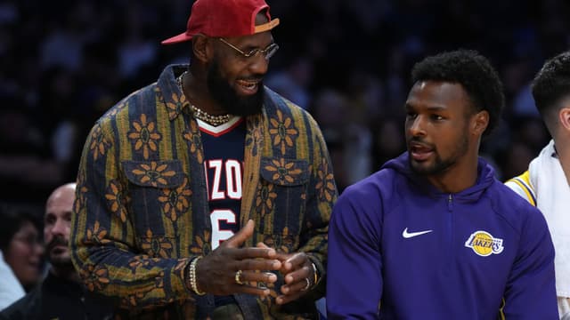 Oct 24, 2025; Los Angeles, California, USA; Los Angeles Lakers forward LeBron James (left) and son Bronny James watch from the bench in the second half against the Minnesota Timberwolves at Crypto.com Arena