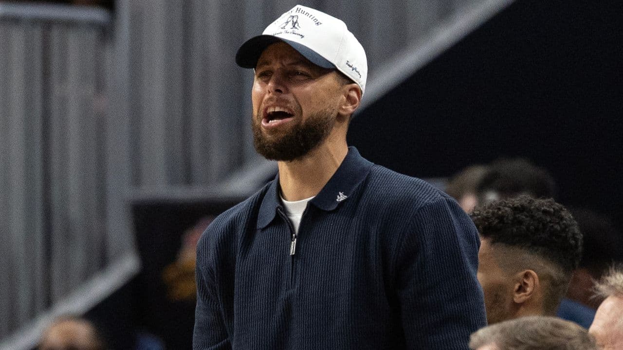 Golden State Warriors guard Stephen Curry (in white baseball hat) cheers on his team against the Los Angeles Clippers during the second quarter at Chase Center.