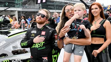 NASCAR Cup Series driver Tyler Reddick (45) stands with his wife, Alexa De Leon, and son, Beau, during the national anthem ahead of the Brickyard 400, Sunday, July 21, 2024, at Indianapolis Motor Speedway.