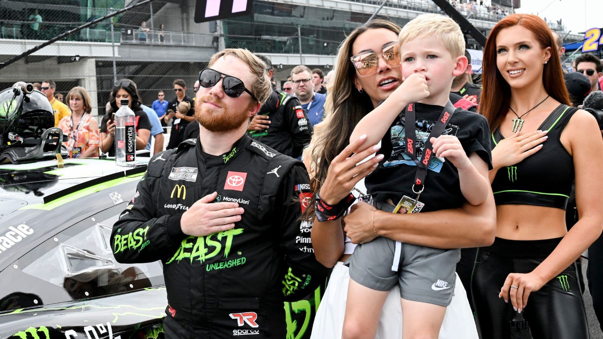 NASCAR Cup Series driver Tyler Reddick (45) stands with his wife, Alexa De Leon, and son, Beau, during the national anthem ahead of the Brickyard 400, Sunday, July 21, 2024, at Indianapolis Motor Speedway.