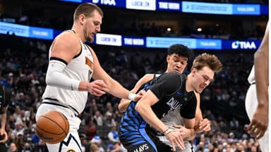 Dallas Mavericks forward Cooper Flagg (32) is fouled by Denver Nuggets forward Spencer Jones (21) as center Nikola Jokic (15) looks on during the second half at the American Airlines Center.