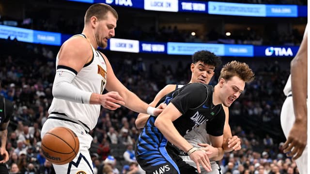 Dallas Mavericks forward Cooper Flagg (32) is fouled by Denver Nuggets forward Spencer Jones (21) as center Nikola Jokic (15) looks on during the second half at the American Airlines Center.